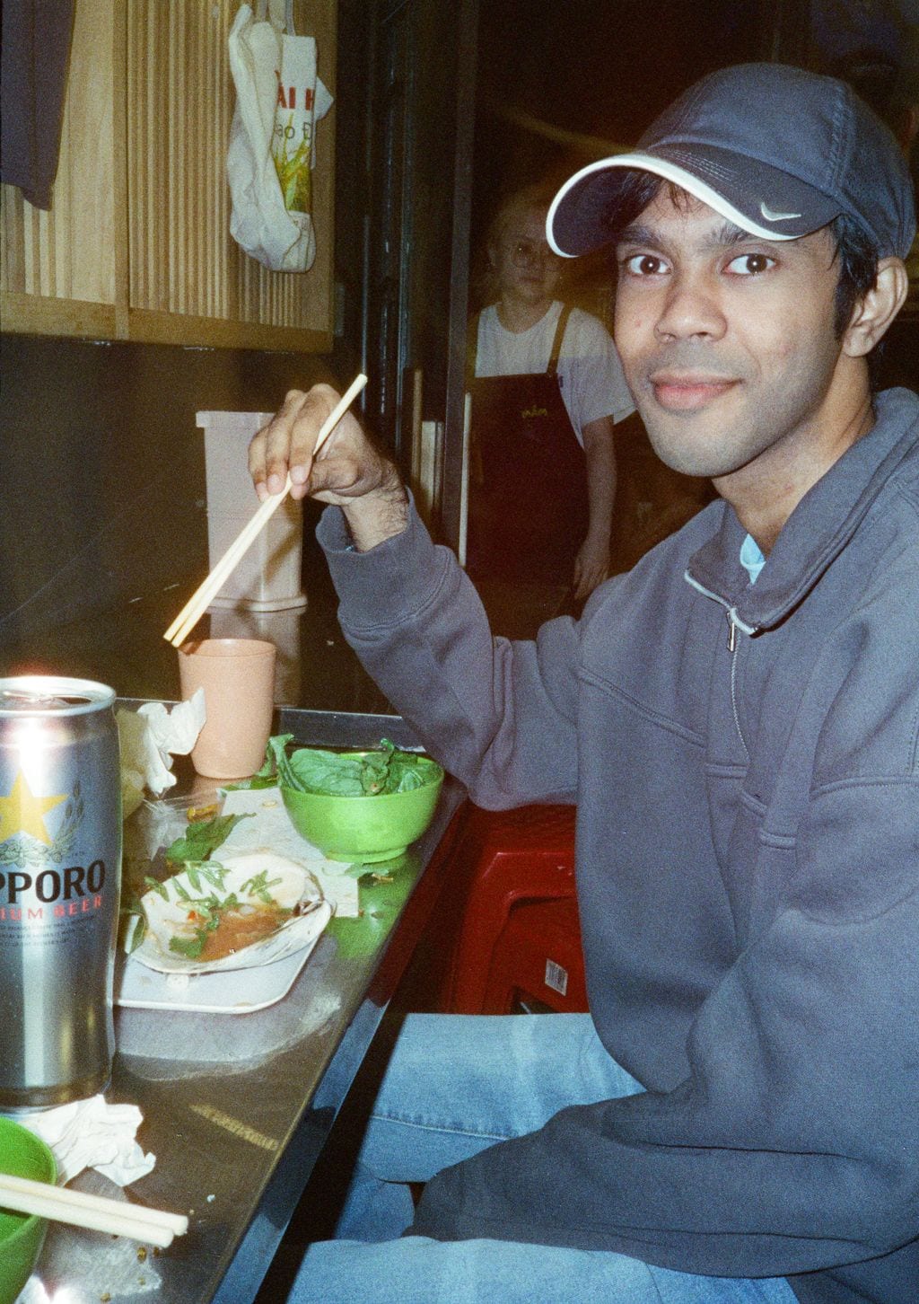A friend at a noodle bar with a Sapporo — 35mm