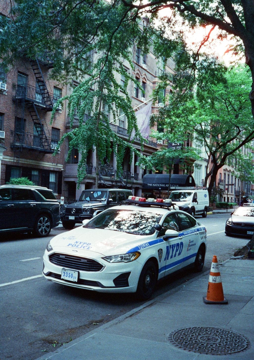NYPD cruiser on a tree-lined street — 35mm