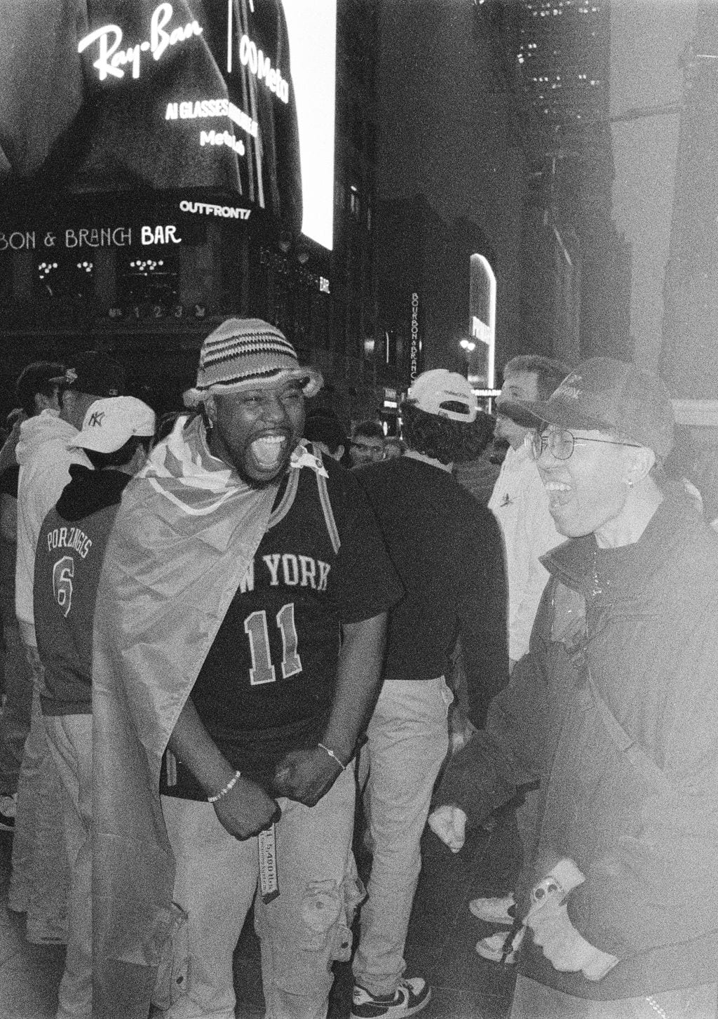 Knicks fan draped in a flag, Times Square at night — 35mm